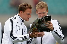 Die Nationalspieler Benedikt Höwedes und Andre Schürrle lesen das DFB-Magazin. Foto: getty images