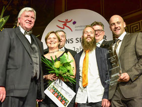Lilien-Spieler Marco Sailer (Mitte, mit Bart) freut sich über die Ehrung von Hessens höchster Stelle, Ministerpräsident Volker Bouffier (li.). Foto: lsbh